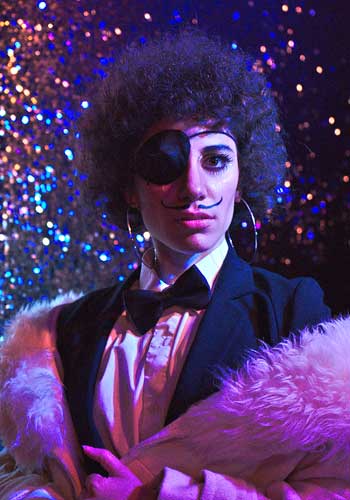 Image: Mojo with eye patch + painted upcurled mustache in evening suit with pink fur collar coat over the shoulders.